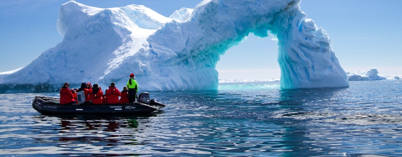 Guests in a Zodiac beside an arched iceberg in Antarctic waters